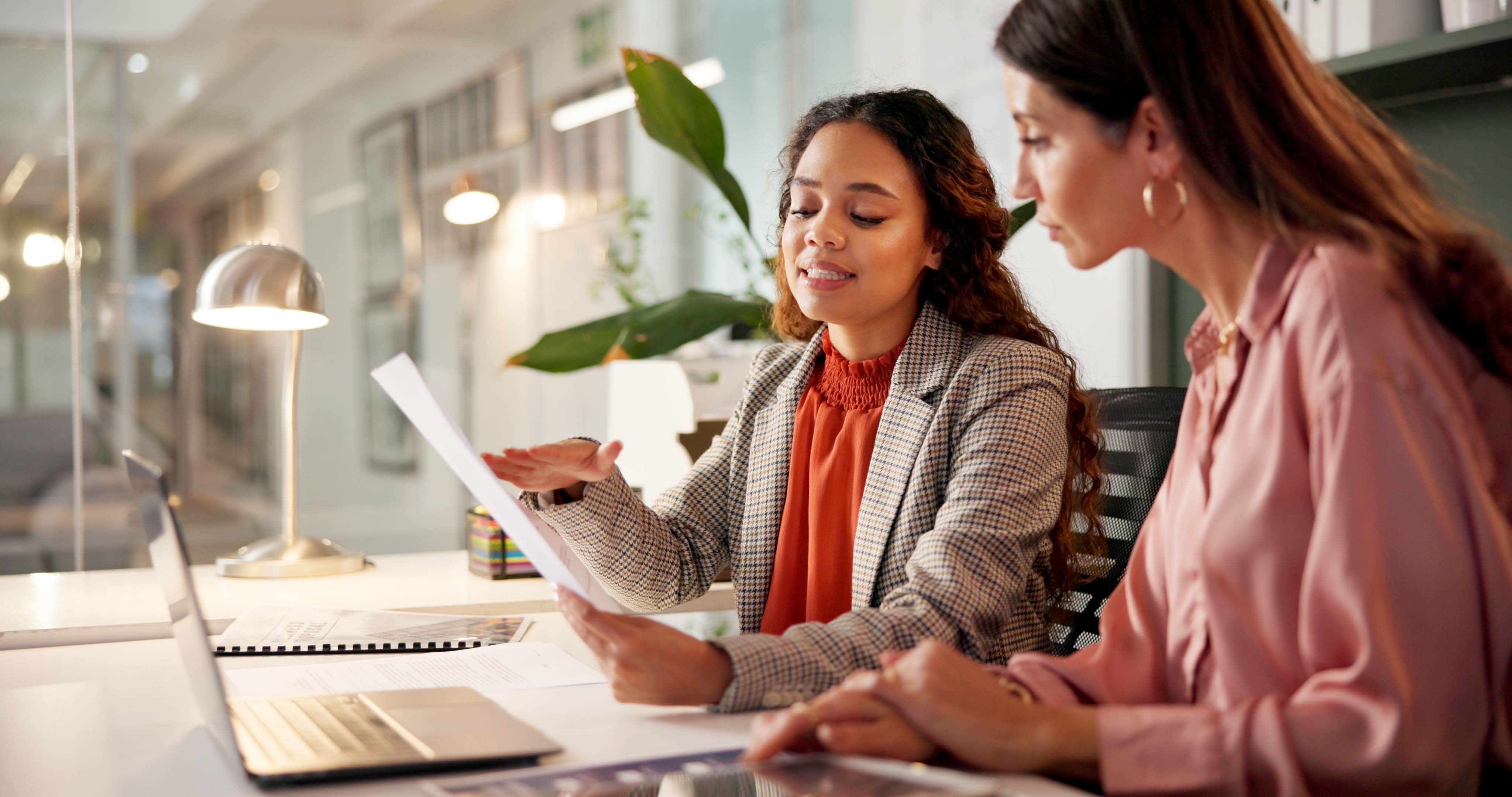 Two colleagues reviewing benefit plan documents together at a desk